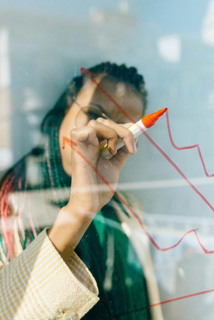 A businesswoman draws a red financial graph on a glass panel, symbolizing strategy and success. Financial planning